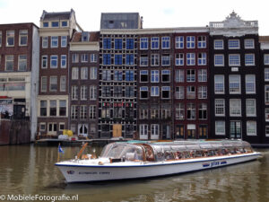 Onderwerp van de foto: rondvaartboot in Amsterdam. Benadrukken: regel van derden, meer ruimte aan voorkant dan aan achterkant, Amsterdamse huizen als achtergrond, boot volledig in beeld. [iPhone 4s]