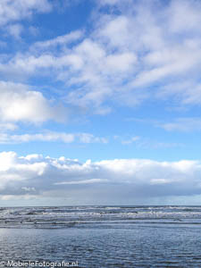 Achtergrondfoto voor je mobiele telefoon: zee met Hollandse wolkenlucht erboven.