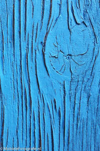 Achtergrond voor je mobiel: Blauwe afbladderende verf met hout-structuur er doorheen.