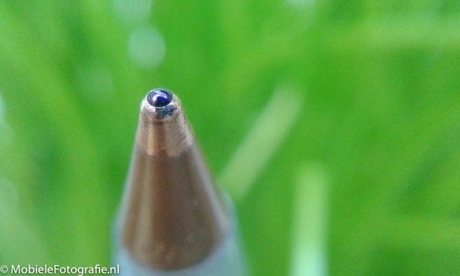 Foto van de punt van een pen met een groene plant als achtergrond. [Samsung Galaxy Trend plus met easy-macro lens]