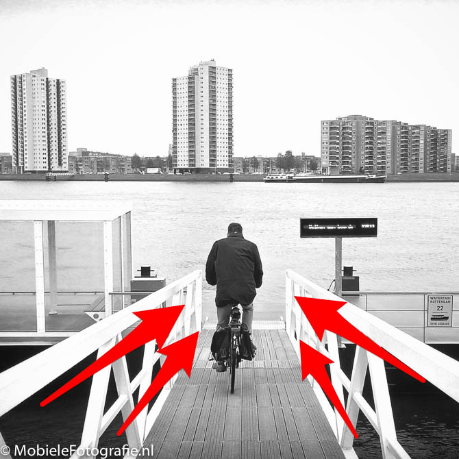 Leidende lijnen door een brugleuning richten je blik op de fietser.