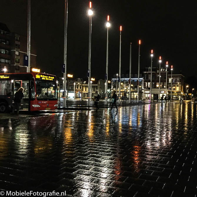 Foto van de Lichten van het busstation in Haarlem die reflecteren in de natte straat. [iPhone 6]