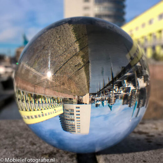 De glazen bol werk als een soort lens waarin Rotterdam Zuid omgekeerd wordt afgebeeld. [Microsoft Lumia 640 LTE]